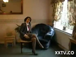 Klassisk kvinne i sexy antrekk borer sin barberte fitte med en svart dildo, i sofaen.