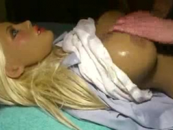 Une poupée blonde douce avec de petits seins est allongée sur le lit comme elle aime beaucoup